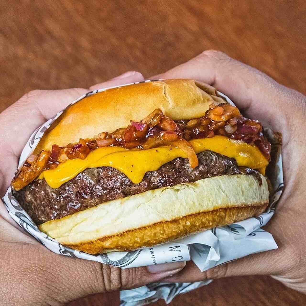 Na foto, uma mão segurando um cheeseburger - Metrópoles