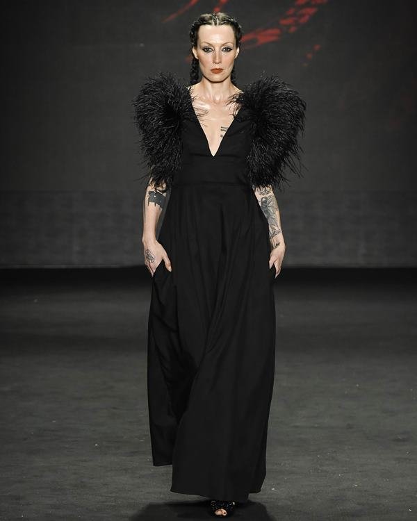 Mulher desfilando com roupas pretas em semana de moda - Metrópoles