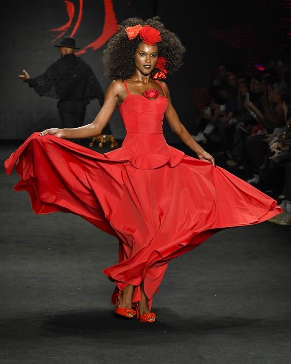Mulher posando com vestido vermelho em desfile de semana de moda - Metrópoles