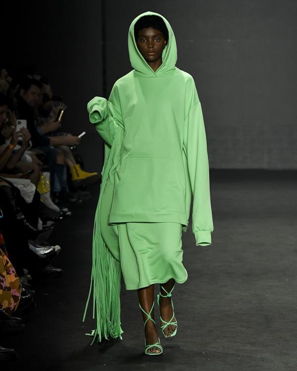 Modelo desfilando em passarela com roupas verde - Metrópoles