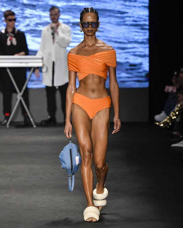 Modelo usa biquíni laranja na passarela e segura bolsa azul com sandália almofada - Metrópoles