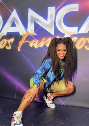 Juliana Alves agachada com short verde neon e jaqueta jeans - Metrópoles