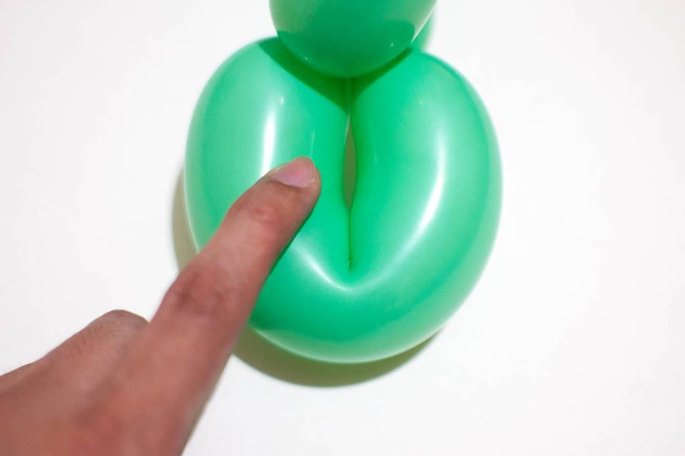 Homem colocando o dedo em um balão em formato de ânus - Metrópoles