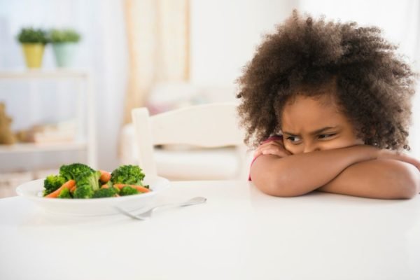 Na foto, uma criança emburrada olhando para a comida - Metrópoles