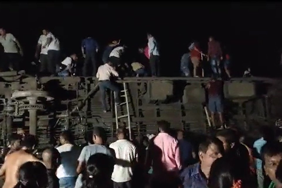 Imagem de uma multidão tentando resgatar vítimas de acidente ferroviário na Índia - Metrópoles