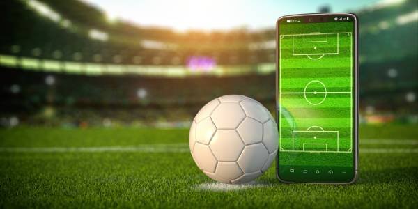 Fotografia colorida mostrando bola ao lado de celular dentro de estádio-Metrópoles