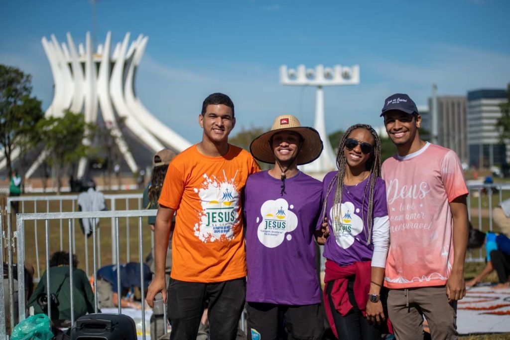 Fieis se abraçam e posam para foto. Catedral ao fundo