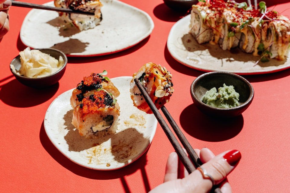 Na foto, uma mesa vermelha com vários pratos com sushi - Metrópoles
