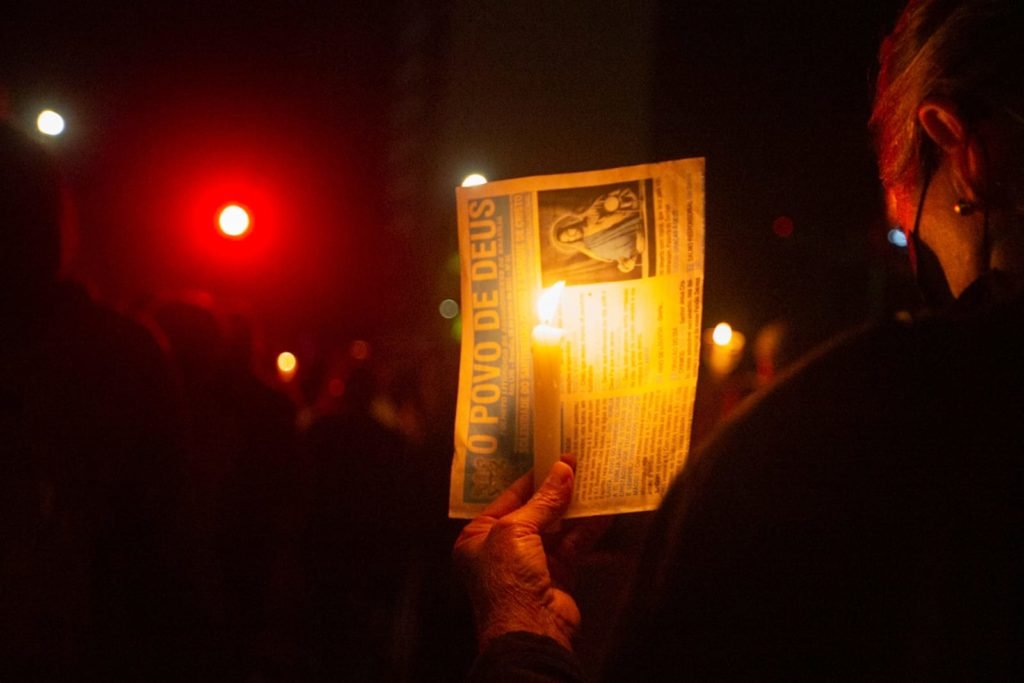 Segurando velas, fiéis participam da procissão com o Santíssimo Sacramento, que percorre o quadrilátero da Esplanada dos Ministérios de frente para a Catedral de Brasília. O Santíssimo Sacramento é transportado no mesmo papamóvel usado na visita do Papa João Paulo II a Brasília.