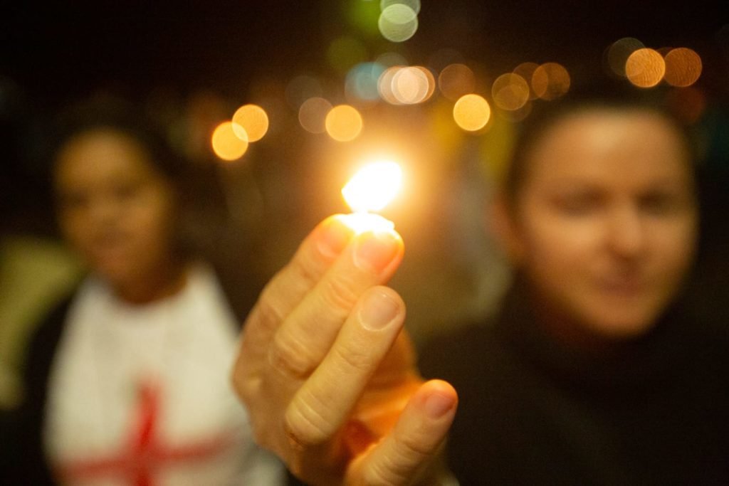 Segurando velas, fiéis participam da procissão com o Santíssimo Sacramento, que percorre o quadrilátero da Esplanada dos Ministérios de frente para a Catedral de Brasília. O Santíssimo Sacramento é transportado no mesmo papamóvel usado na visita do Papa João Paulo II a Brasília.