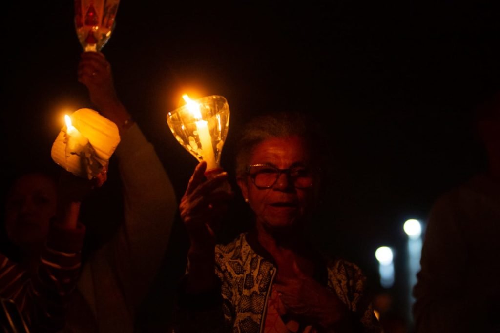 Segurando velas, fiéis participam da procissão com o Santíssimo Sacramento, que percorre o quadrilátero da Esplanada dos Ministérios de frente para a Catedral de Brasília. O Santíssimo Sacramento é transportado no mesmo papamóvel usado na visita do Papa João Paulo II a Brasília.
