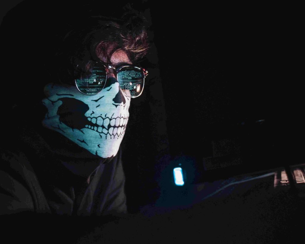 Imagem de homem com máscara na frente do computador