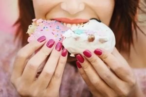 Imagem colorida: mulher comendo doce - Metrópoles