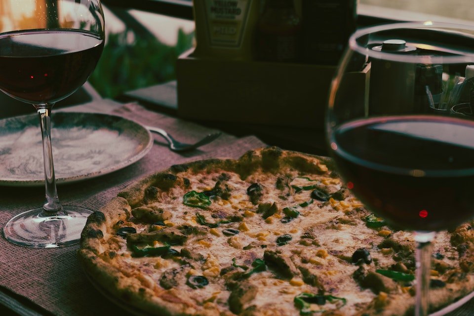 Na foto, uma mesa com pizza e duas taças de vinho - Metrópoles