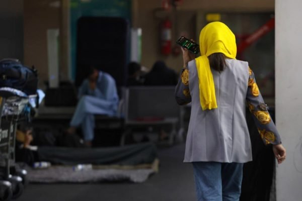 refugiada afegã fala ao telefone no aeroporto de guarulhos - metrópoles