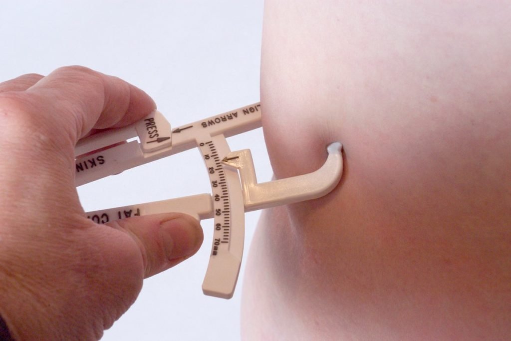 Fotografía en color de una mano sosteniendo un clip para medir la grasa abdominal - Metropolis