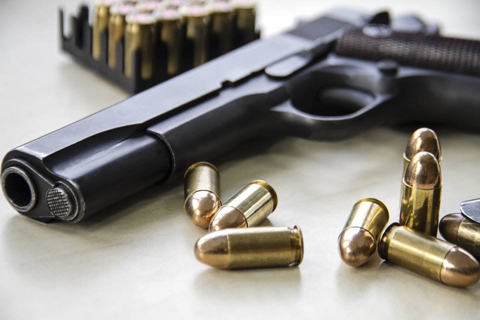 Imagem colorida mostra arma de fogo pistola e alguns projéteis balas - Metrópoles