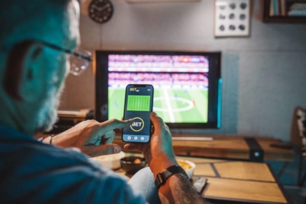 Homem com smartphone, jogador fazendo apostas de futebol. vício em jogos de  azar no celular, aplicativo de apostas esportivas, previsão de resultados  de partidas de futebol.