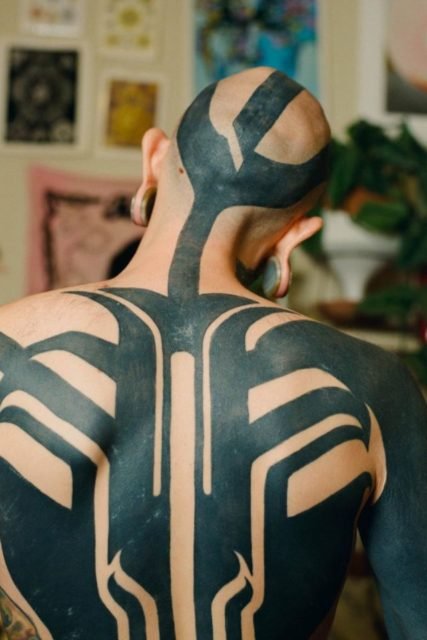 Na foto, homem com as costas tatuada de preto - Metrópoles