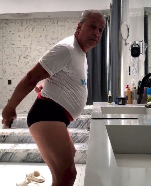 Sikêra Jr. está utilizando uma camisa branca e uma cueca preta. Ele está em um banheiro, é branco e tem o cabelo branco - Metrópoles