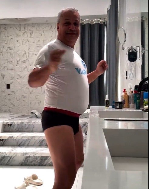 Sikêra Jr. está utilizando uma camisa branca e uma cueca preta. Ele está em um banheiro, é branco e tem o cabelo branco - Metrópoles