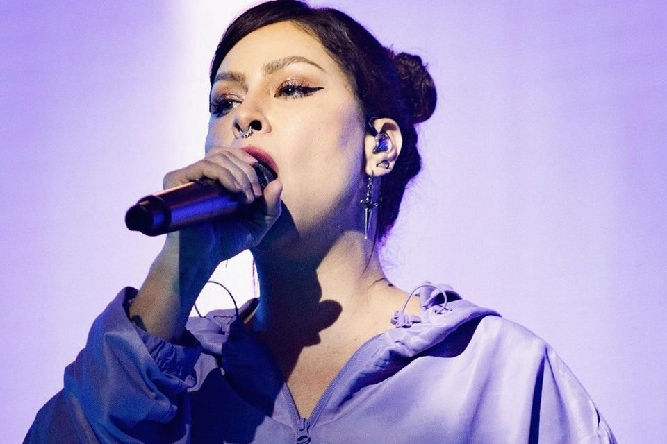 Foto colorida da cantora Pitty. Ela está com um microfone na mão, cantando e utiliza uma roupa roxa - Metrópoles