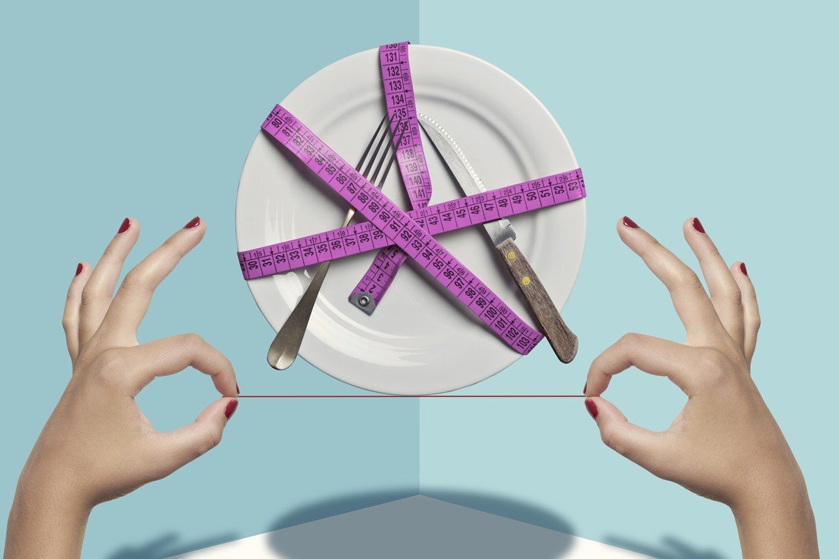 Foto colorida de prato em cima de um fio, segurado por duas mãos. O objeto e talheres estão amarrado com uma fita métrica, na cor roxa - Metrópoles