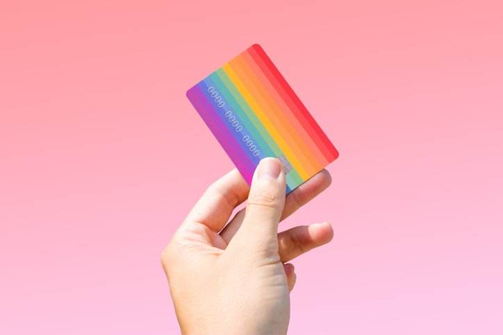 Pink money: imagem de pessoa segurando um cartão de crédito com as cores do movimento LGBT. Cor rosa de fundo