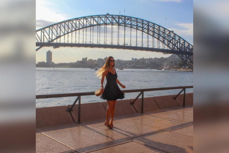 Mulher com vestido preto em frente a uma ponte - Metrópoles