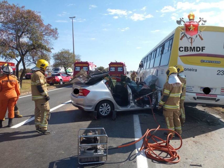 Imagem colorida de acidente em que umm carro prata bateu na traseira de ônibus amarelo