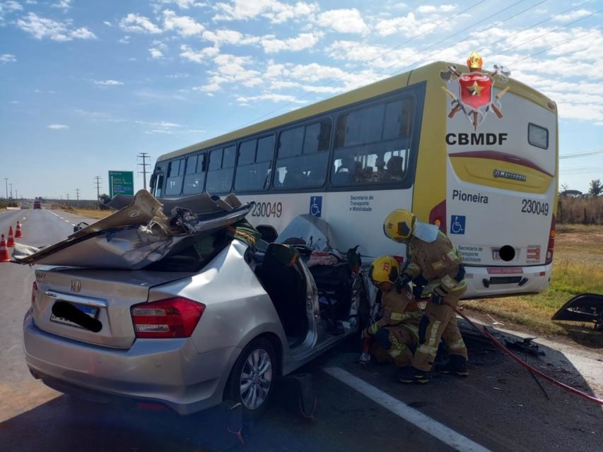 Imagem colorida de acidente em que umm carro prata bateu na traseira de ônibus amarelo