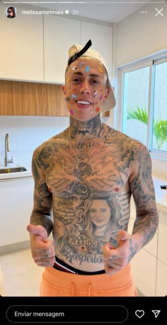 MC Daniel posa todo coberto de adesivos, de boné e bermuda laranja - Metrópoles