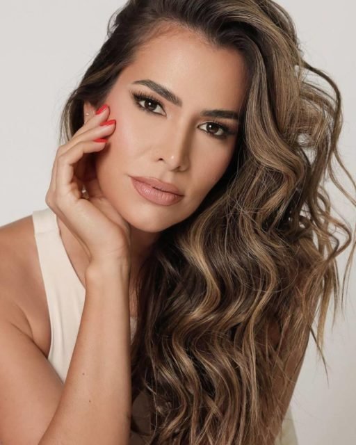 Foto colorida de Adriana Sant'anna. Ela tem os cabelos claros, é branca e utiliza uma camisa branca. A ex-BBB faz carão para a foto - Metrópoles