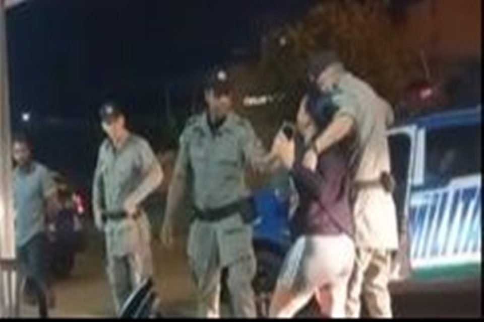 Imagem mostra mulher sendo segurada por dois policiais militares
