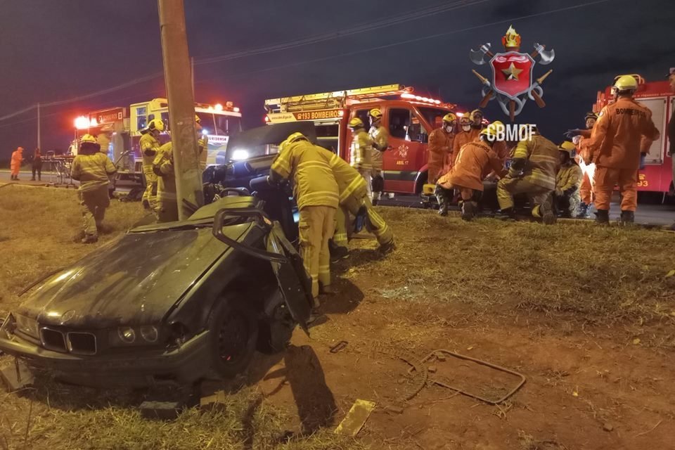Foto de um carro BMW preto batido em poste