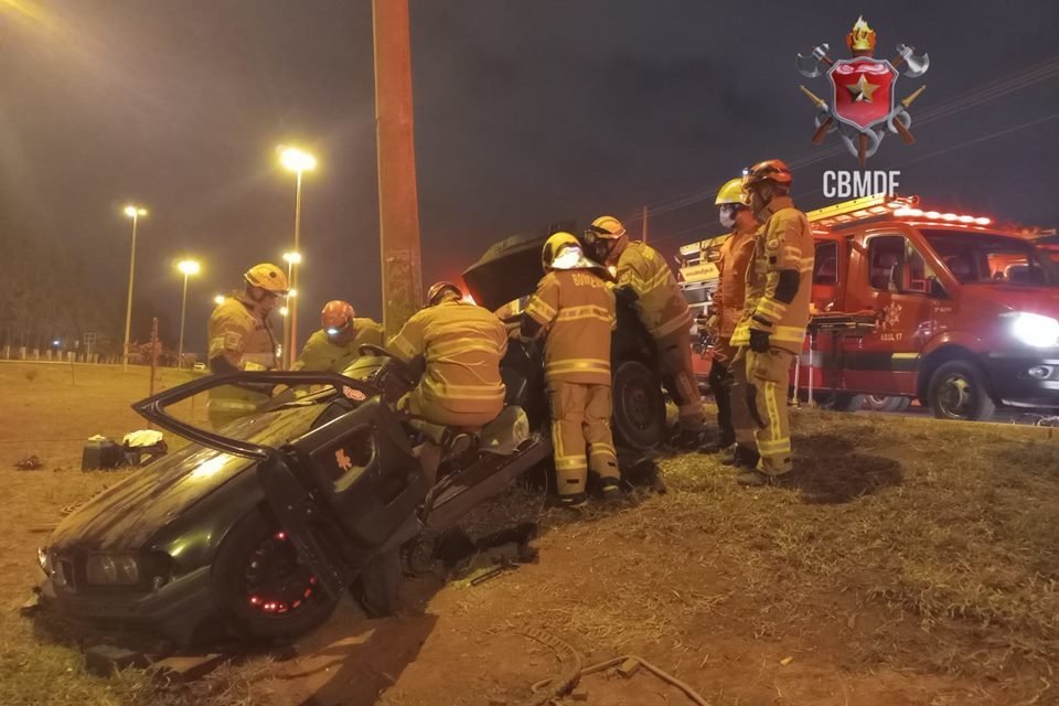 Foto de um carro BMW preto batido em poste