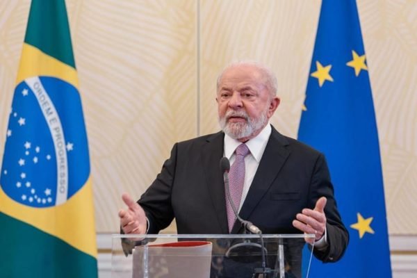 imagem colorida de Lula em entrevista coletiva na Bélgica, com as bandeiras do Brasil e da União Europeia ao fundo - Metrópoles
