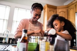 Na foto, uma mulher e uma criança negras cozinhando na cozinha - Metrópoles