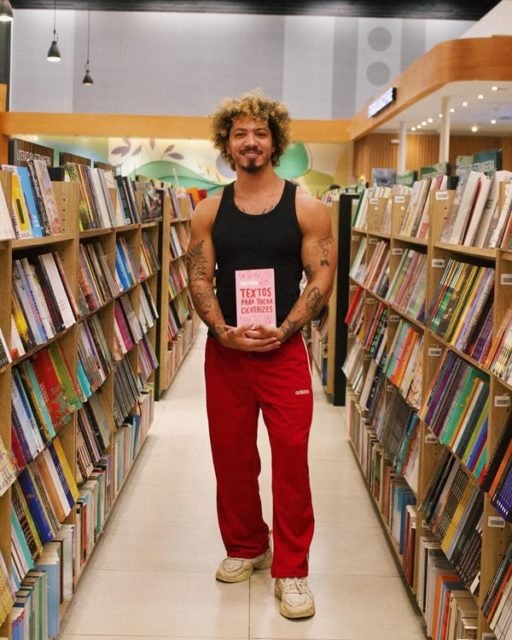 Igor Pires, fundador da marca e da página Textos Crueis Demais para Serem Lidos Rapidamente, no meio de um corredor de livros