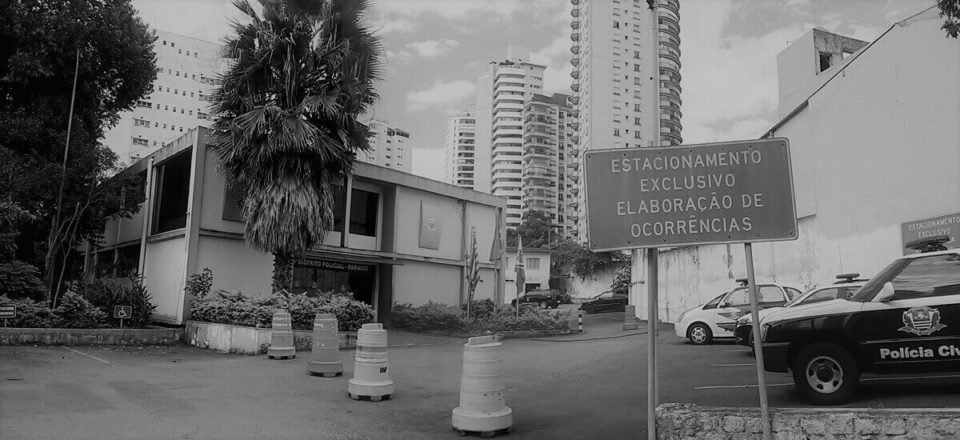 Fotografia em preto e branco da fachada de uma delegacia - Metropoles