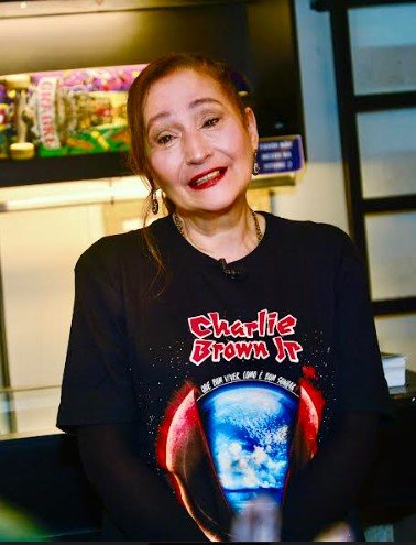 Foto colorida de Sonia Abrão chorando usando a blusa de Chorão - Metrópoles