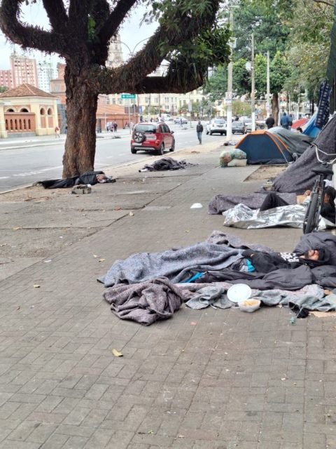 Imagem mostra pessoas deitadas na calçada, com cobertores, no entorno do Parque da Luz, em São Paulo - Metrópoles