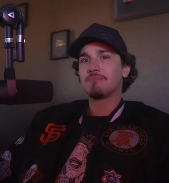 Frame de um vídeo do Instagram de Christian Figueiredo. O youtuber chora enquanto desabafa. Ele está usando um boné preto, casaco preto com detalhes em vermelho e uma blusa preta - Metrópoles