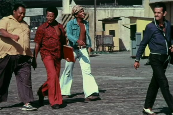 Imagem do filme Ladrões de Cinema. Na imagem, quatro homens aparecem andando, com roupas coloridades - Metrópoles