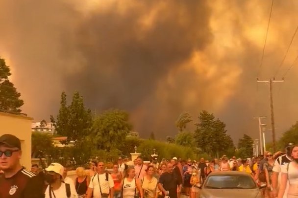 Imagem colorida de dezenas de pessoas andando na rua para fugir de incêndio na Grécia- Metrópoles