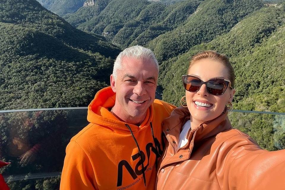 Foto colorida de Ana Hickmann e Alexandre Correa. Ela está de óculos de sol, com uma roupa laranja. Ele está de casaco laranja - Metrópoles