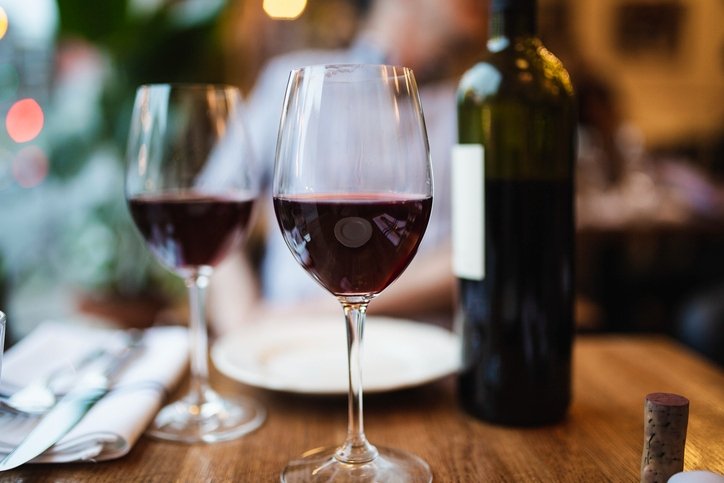 Foto mostra mesa posta com duas taças de vinho dispostas ao lado de uma garrafa - Metrópoles