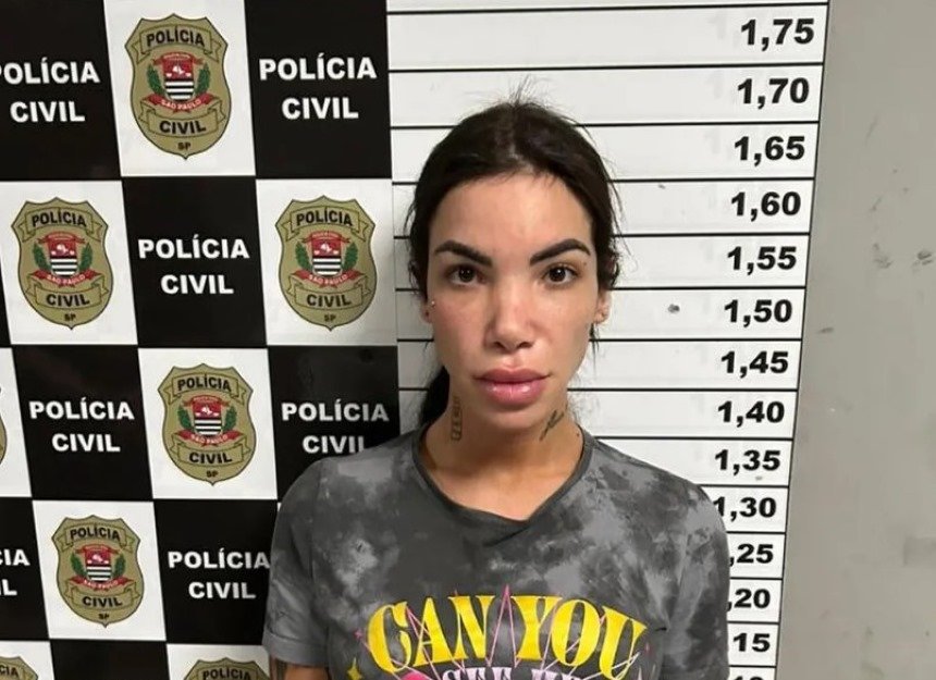 Influencer Vitória Guarizo Demito de cabelo preso em sala da Polícia Civil com marcação de altura; ela foi presa por roubar e torturar homem