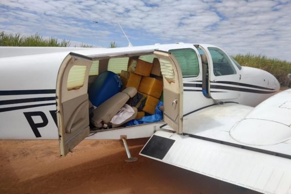 Avião branco com portas abertas e vários pacotes fechados contendo mais de 500 kg de cocaina