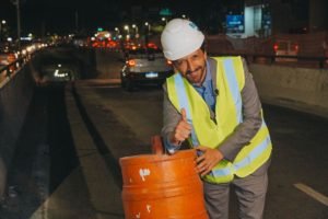 Imagem colorida mostra o prefeito Ricardo Nunes, de terno cinza, vestindo colete florescente e capacete de proteção para obras. Ele está apoiado em um cone de trânsito e faz sinal de positivo com a mão - metrópoles